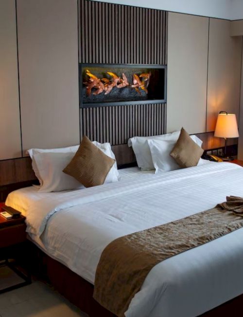 A cozy hotel room features a large bed with decorative pillows, bedside tables with lamps, and curtains on the window.