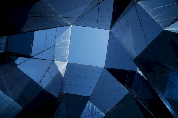 Geometric glass structures create a window to the sky, reflecting light and forming an abstract architectural pattern.