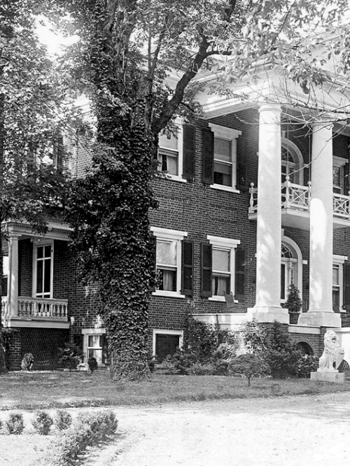 A large, historic brick house with tall columns, surrounded by trees and a manicured lawn, is featured in the image.